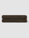 Two dark brown towels from the Cozy Earth Complete Ribbed Terry Bath Bundle are neatly rolled and stacked atop each other against a plain light gray background.|Color:Espresso