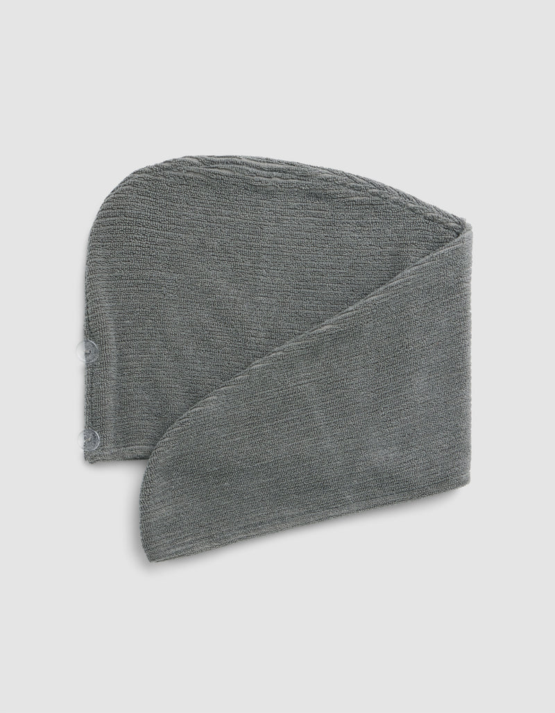 The Cozy Earth Ribbed Terry Hair Towel in grey is pictured folded in a spiral shape against a light grey background.