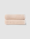 The Cozy Earth Complete Ribbed Terry Bath Bundle features two neatly folded, light beige towels stacked atop each other against a plain, light gray background.|Color:Petal