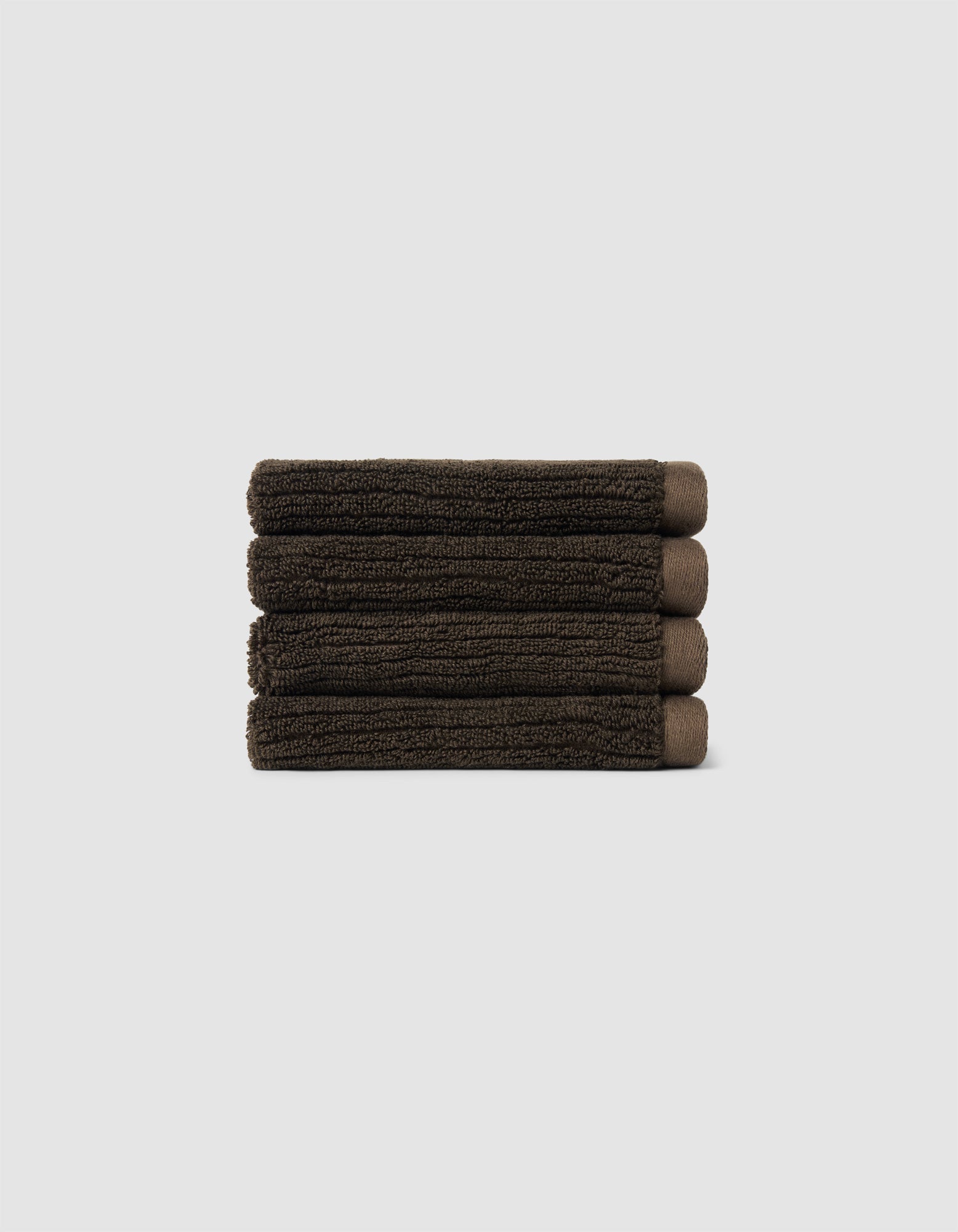 The Cozy Earth Complete Ribbed Terry Bath Bundle, featuring four dark brown towels, is arranged horizontally against a plain light gray background.