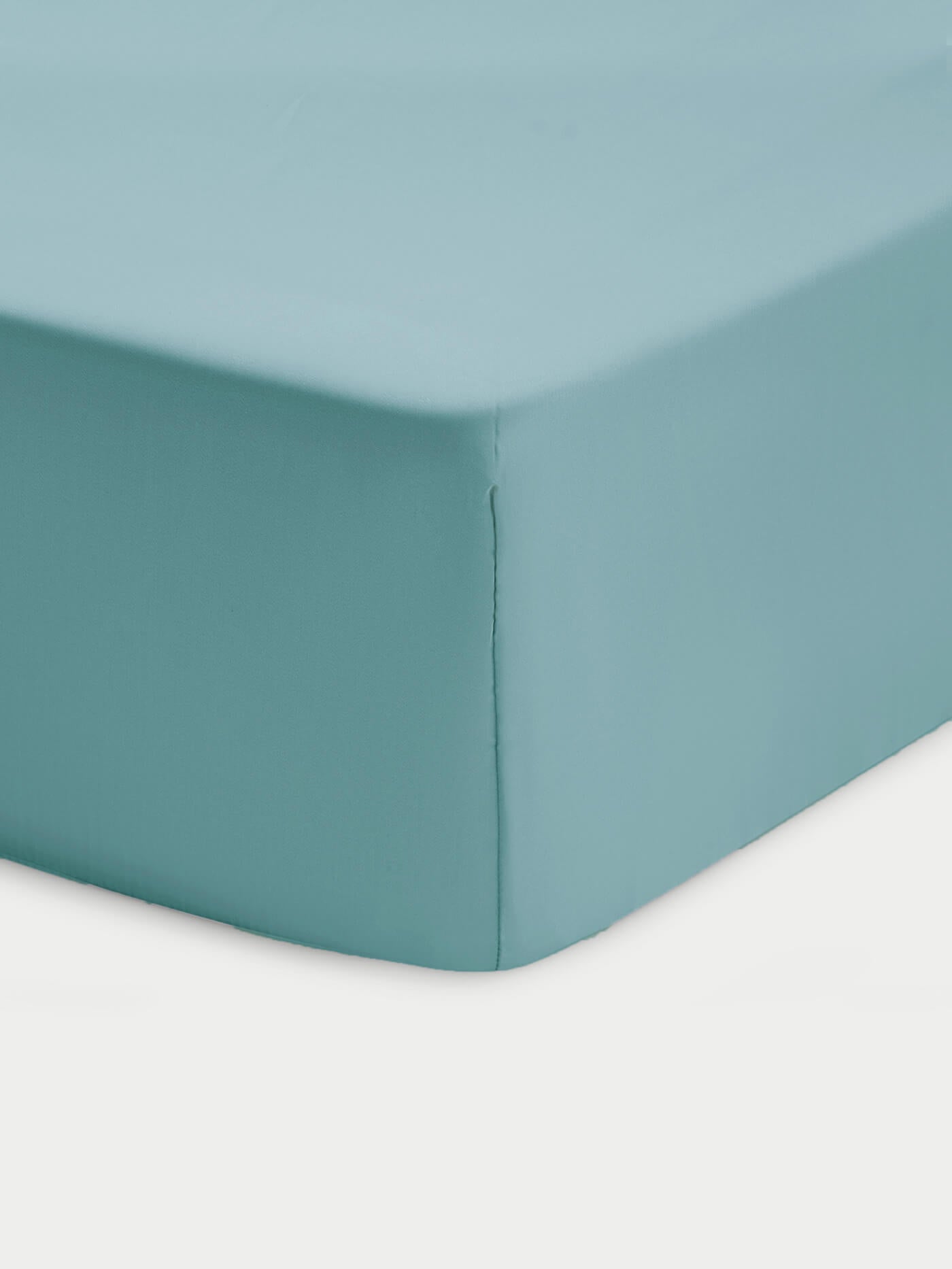 Close-up of a corner of a bed showcasing the Cozy Earth Bamboo Fitted Sheet in light blue, neatly covering the mattress against a white background.