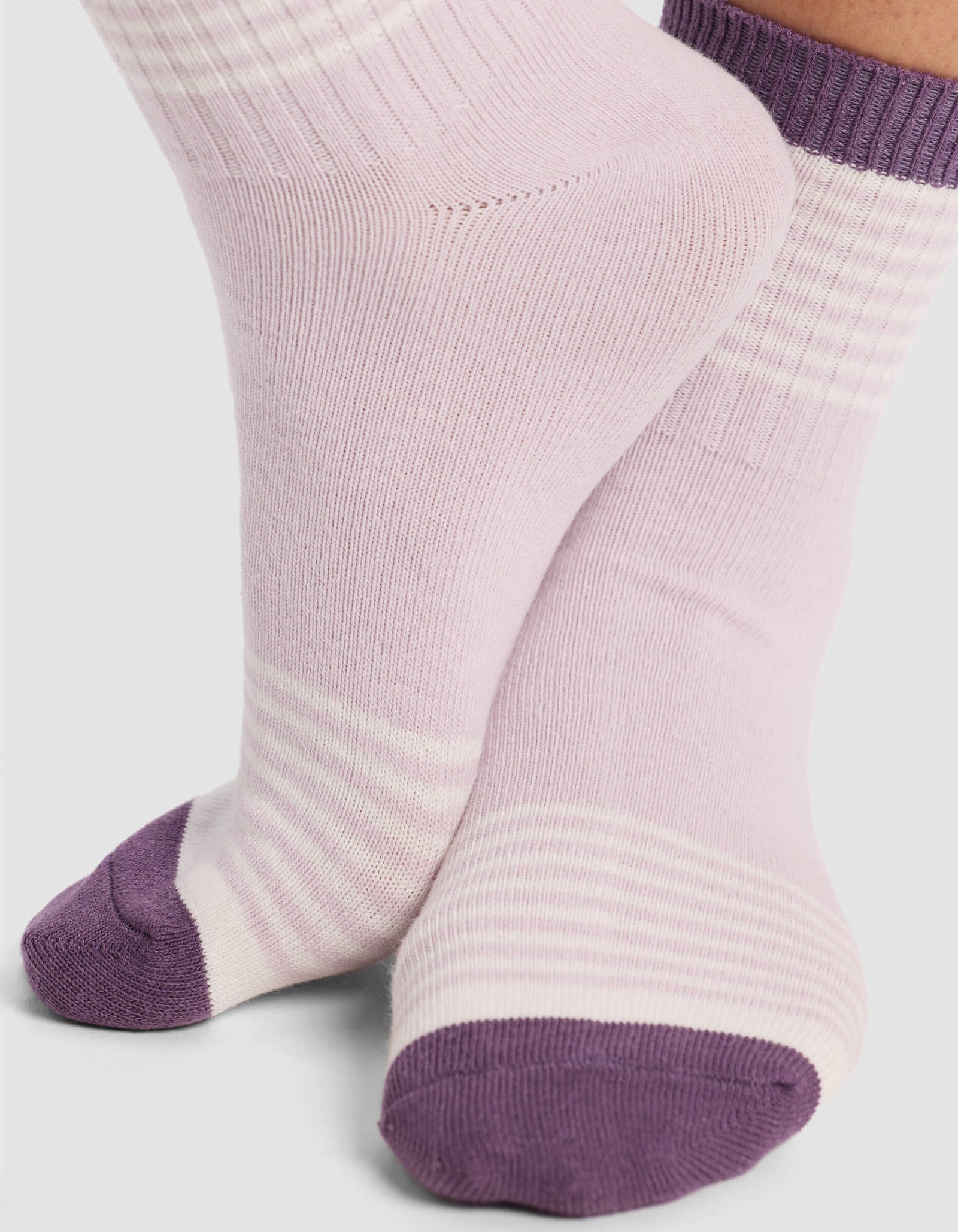 Two feet wearing Cozy Earth Women's Sadie Socks in pastel purple with darker purple toes and cuffs. The socks have subtle light stripes near the ankles and feet, shown against a plain white background.