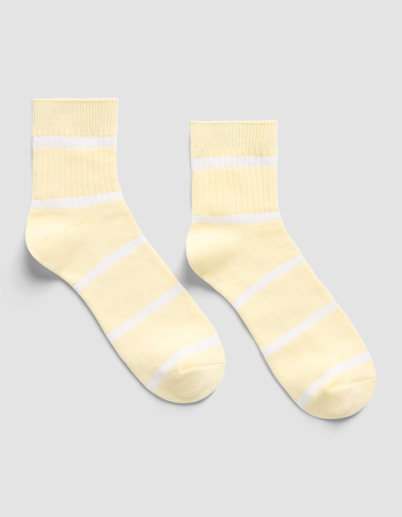 The Cozy Earth Women's Sadie Sock in light yellow with white horizontal stripes is displayed flat on a light gray background.