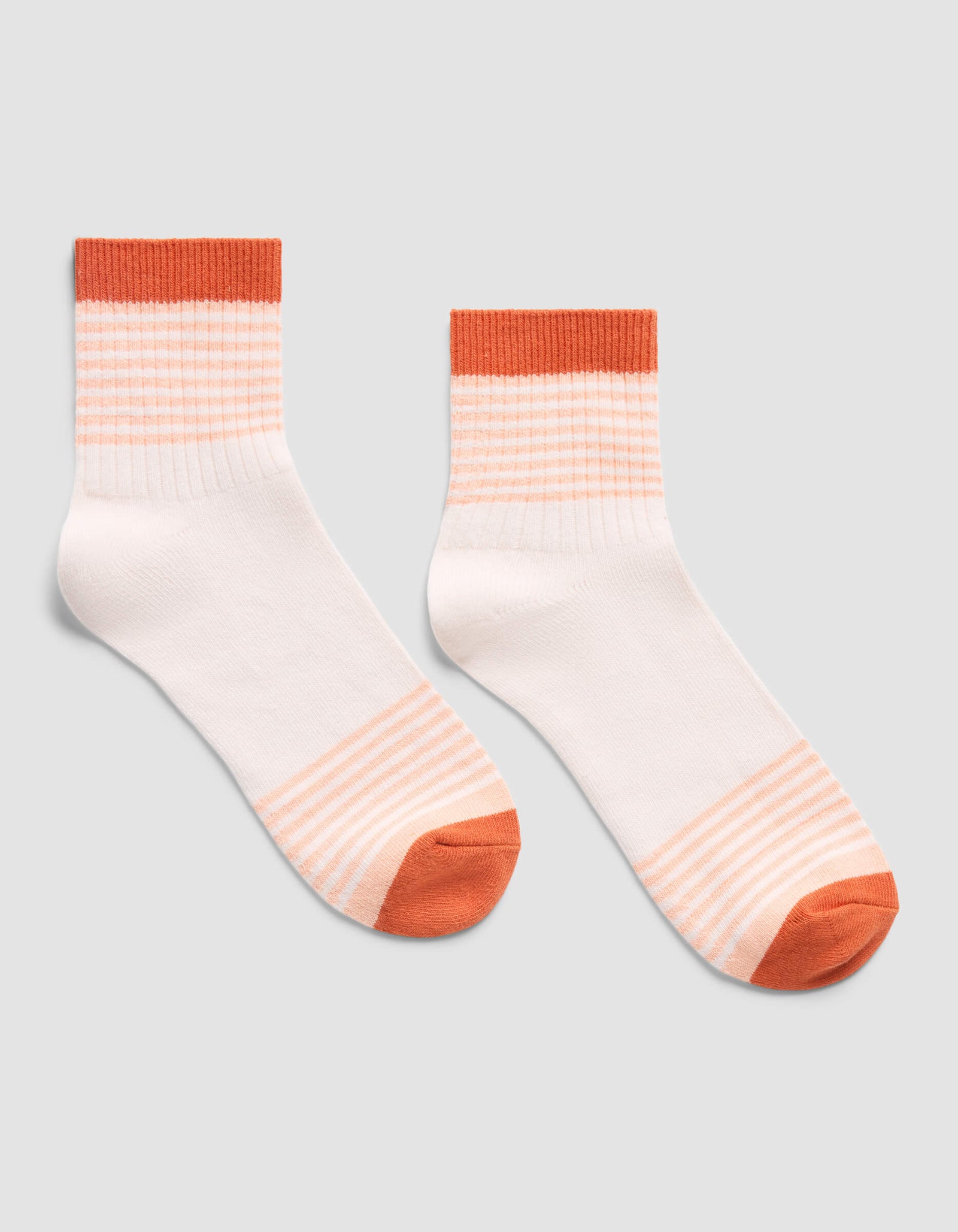 The Cozy Earth Women's Sadie Sock features white ankle socks with orange toes, heels, and cuffs, plus thin orange stripes on the cuffs and near the toe over a light gray background.