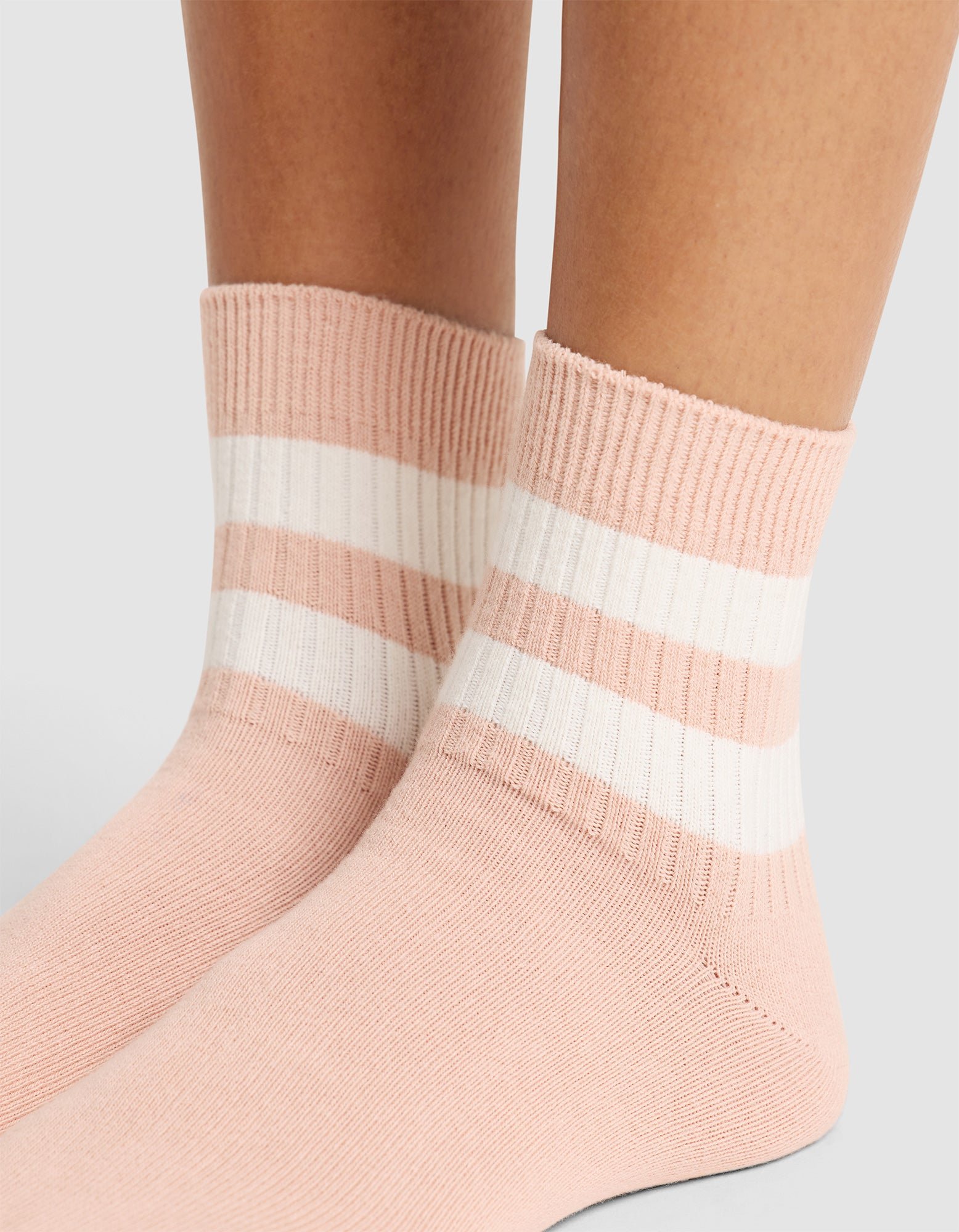 Close-up of two feet wearing Cozy Earth Women's Sadie Socks in light pink with white and pink stripes near the top, against a plain light background. |Color:Dusty Rose/Bone
