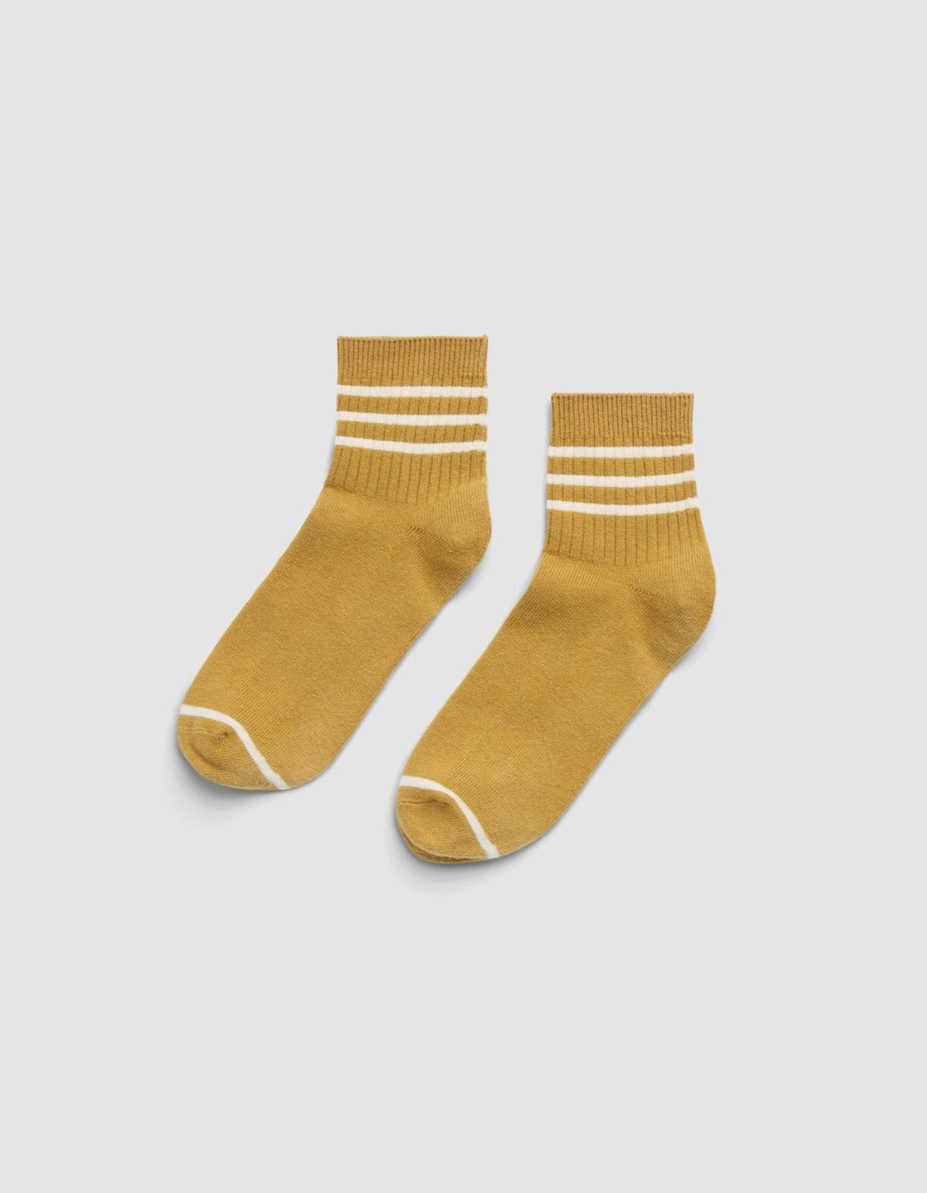 The Cozy Earth Women's Sadie Sock is a mustard yellow ankle sock with two white stripes near the top and white trim at the toe and heel, shown on a light gray background. 