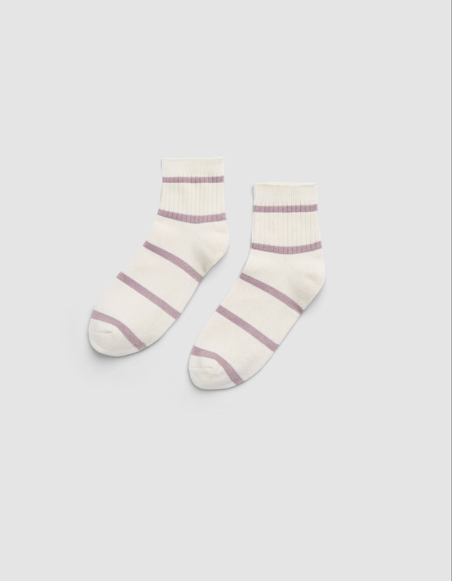 The Women's Sadie Sock by Cozy Earth is a pair of white ankle socks featuring light purple horizontal stripes and ribbed cuffs, displayed flat on a light gray background. 