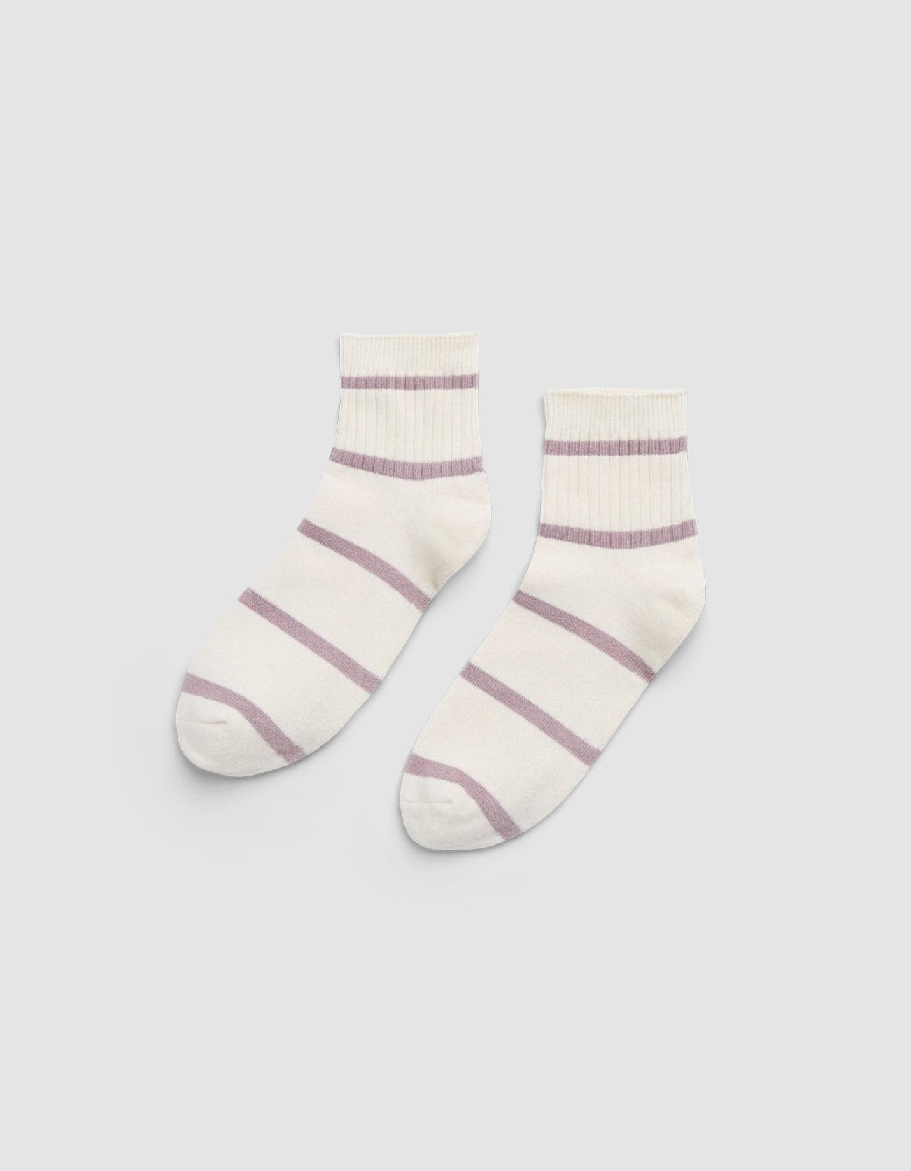 The Women's Sadie Sock by Cozy Earth is a pair of white ankle socks featuring light purple horizontal stripes and ribbed cuffs, displayed flat on a light gray background. 
