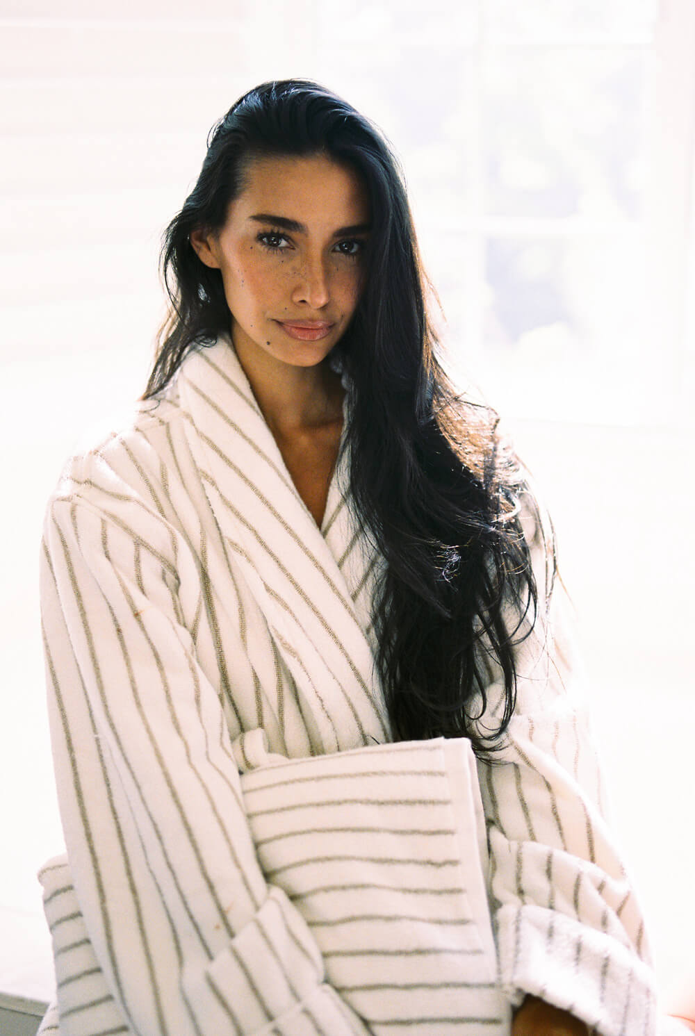 Woman wearing a white striped robe with a blurred background