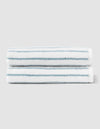 Two Striped Luxe Hand Towels by Cozy Earth, featuring thin teal horizontal stripes on white, are neatly folded and stacked against a light gray background. |Color:Brook Stripe
