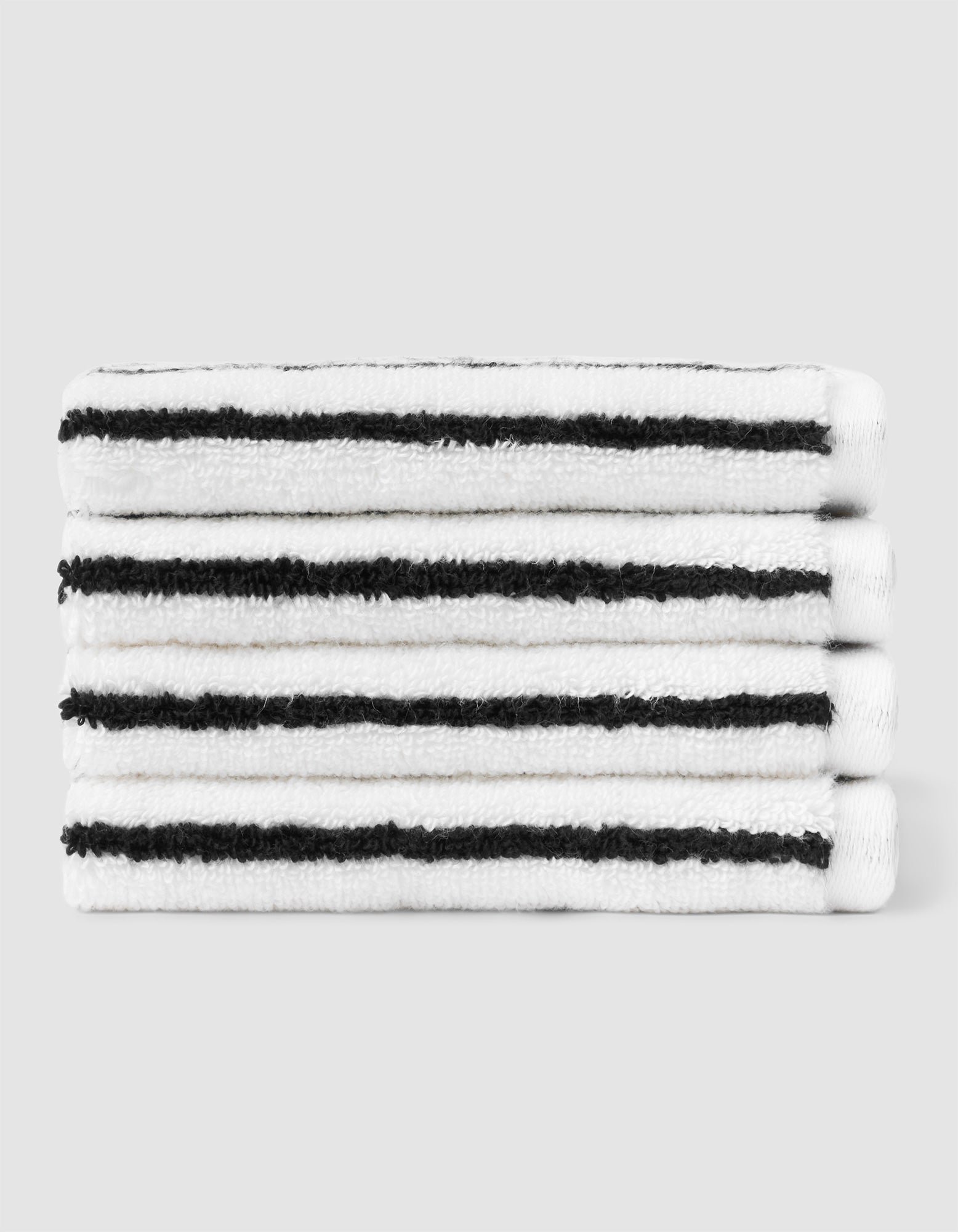 A stack of four neatly folded Cozy Earth Striped Luxe Washcloths in white with evenly spaced black stripes, set against a plain light gray background. |Color:Black Stripe