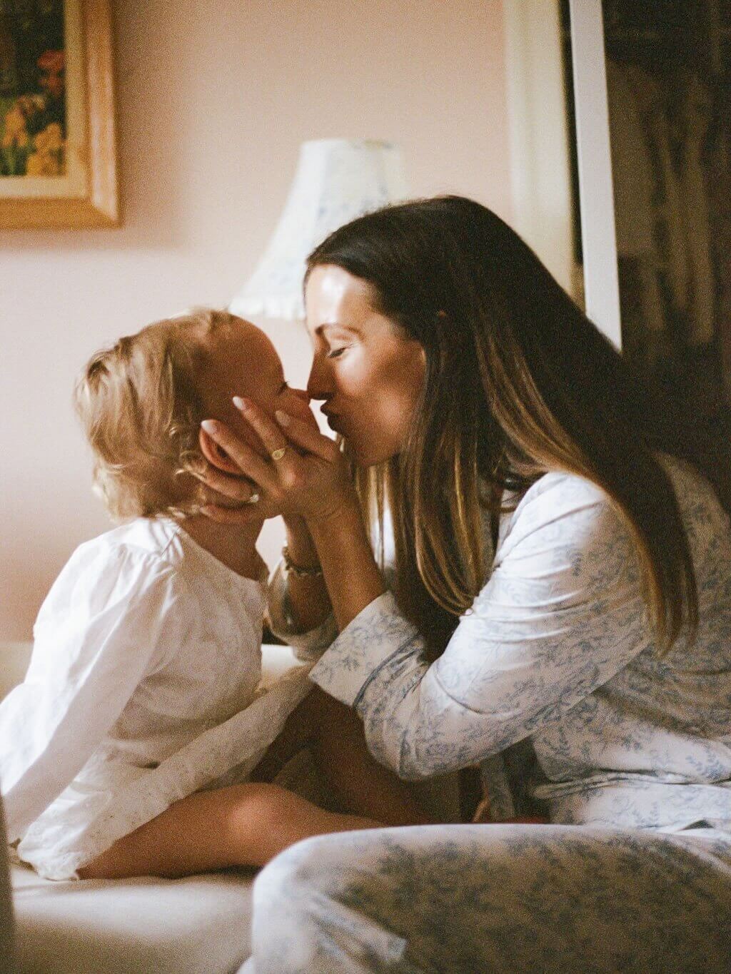 Woman and child sitting close together in a softly lit room.