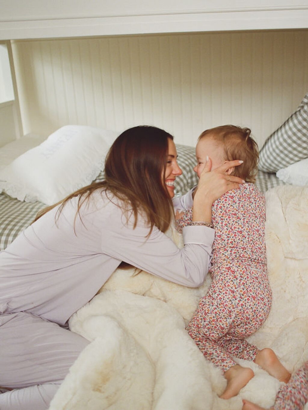 Woman and baby sitting on a bed in a cozy room