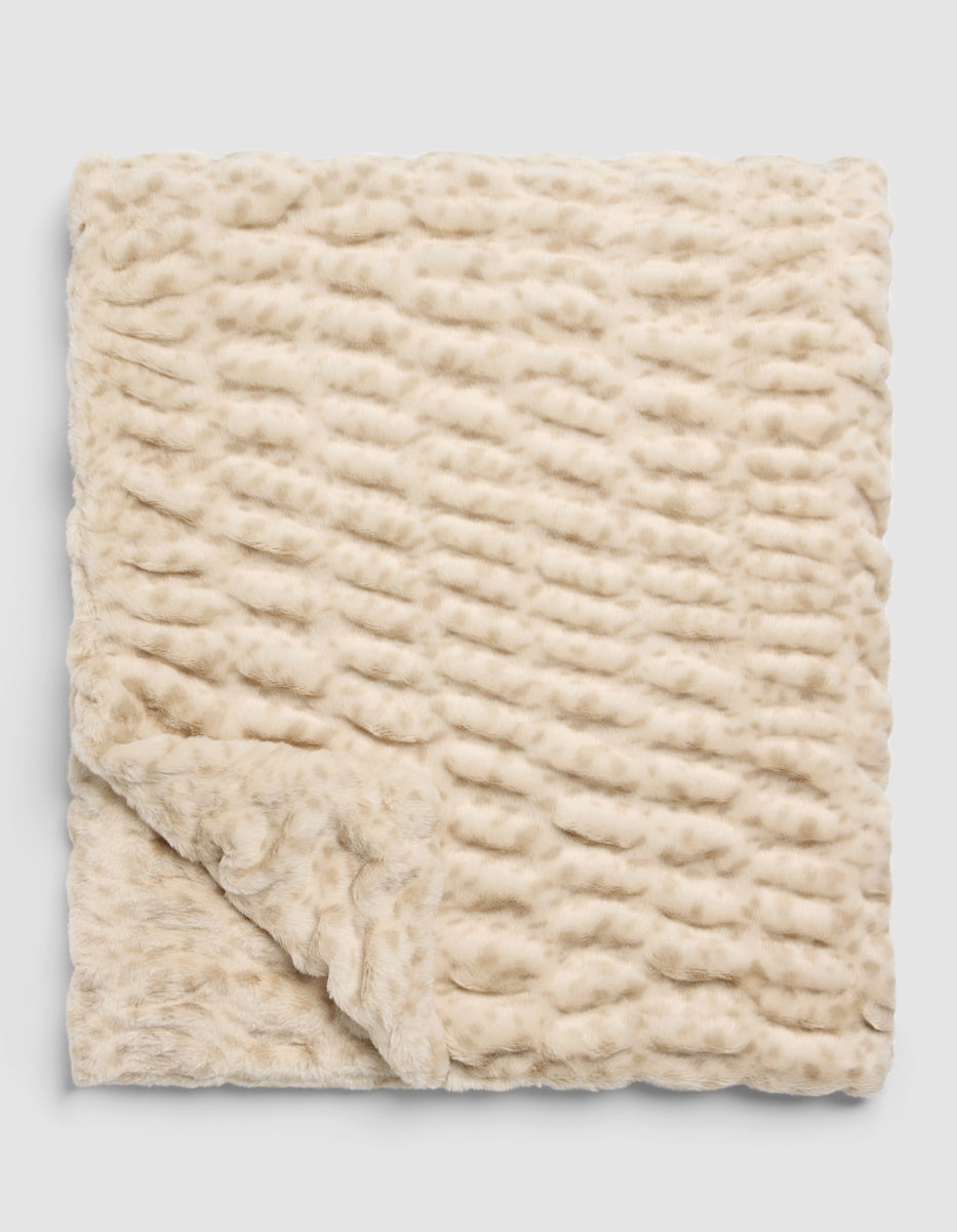 A folded cream-colored Snuggle Cuddle Blanket with a textured, wavy pattern.