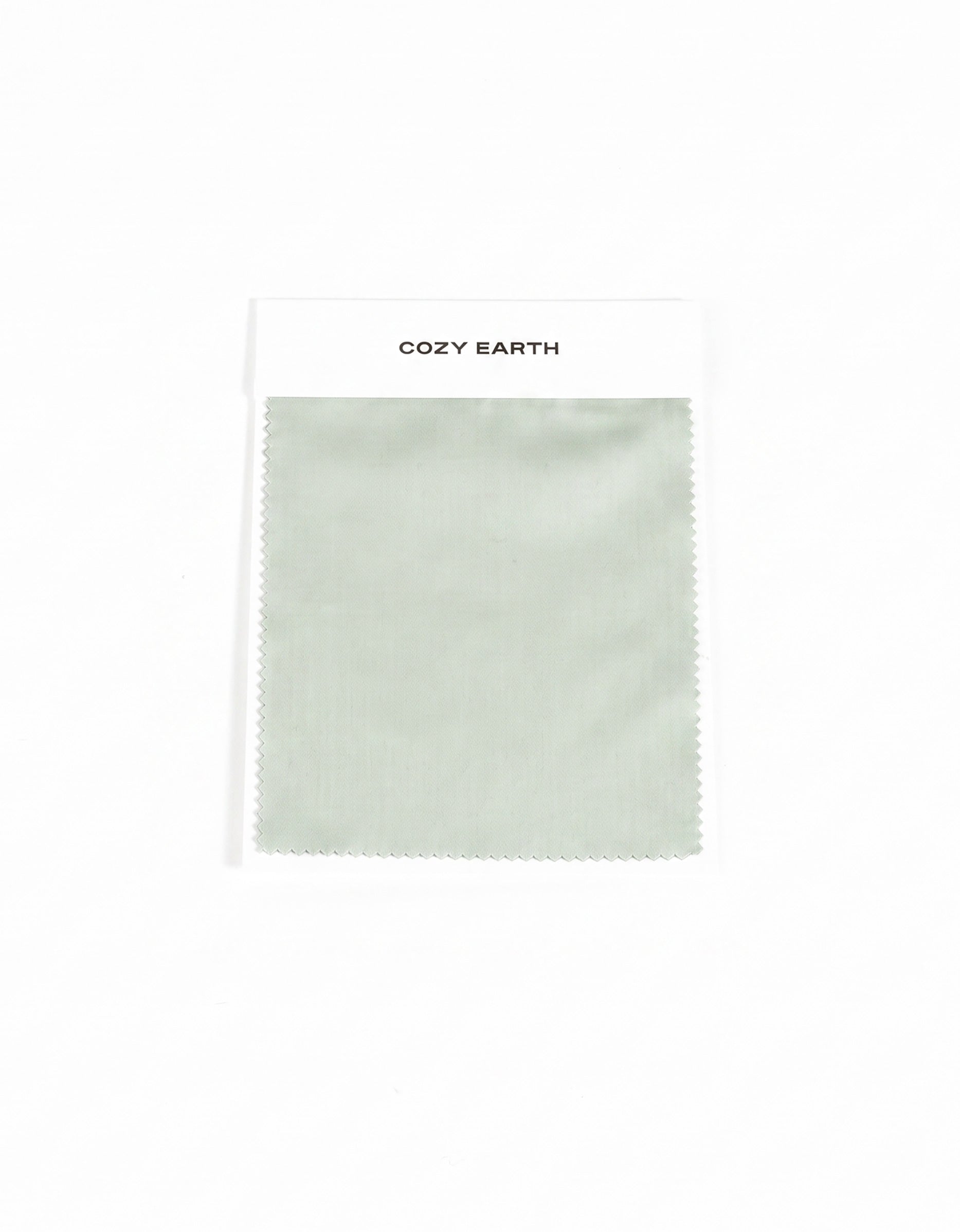 A rectangular Soft-Wash Cotton Sheet Swatch in light sage green is shown on a white card labeled "Cozy Earth" at the top, set against a plain white background.
