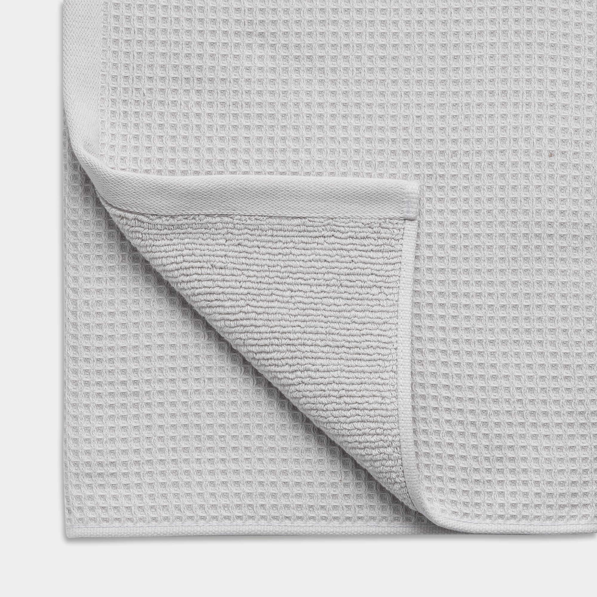 Waffle Bath Towel in the color Light Grey. Photo of Light Grey Waffle Bath Towel taken close up showing the corner of the towel 