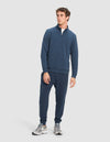 A man wears Cozy Earth's Men's StretchTech Quarter Zip and matching jogger pants with light gray sneakers, standing slightly turned with a neutral expression against a plain light background.|Color:Eclipse
