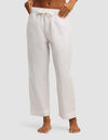 A person stands barefoot against a plain light gray background, wearing Cozy Earth’s Women's Sutton Cropped Pajama Pant—loose-fitting with a white drawstring and cropped just above the ankles.|Color:White