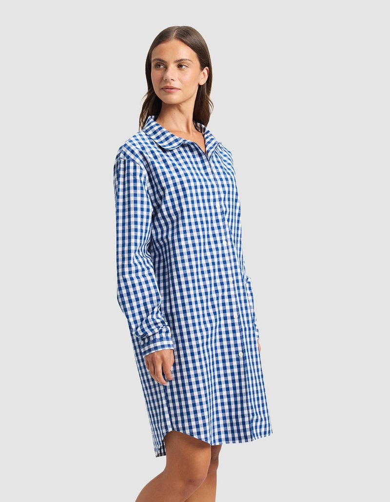 A woman wears the Cozy Earth Women's Sutton Sleep Dress, a blue and white checkered long-sleeve style, standing slightly left against a plain light gray background.