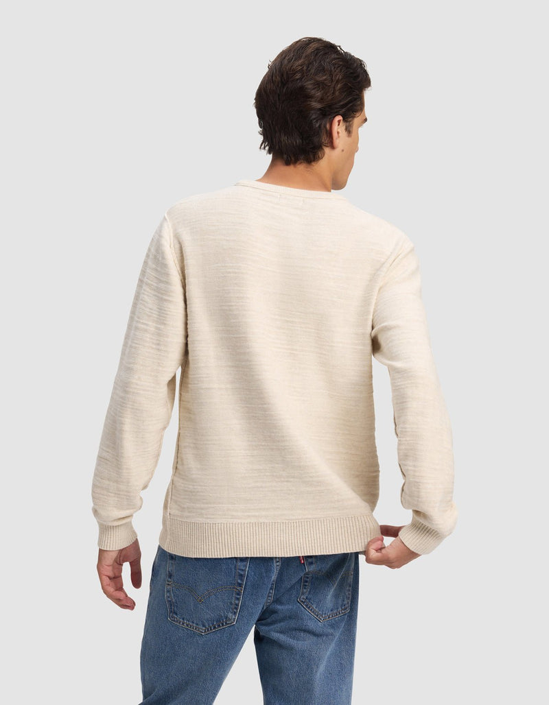 A man with short brown hair wears the Cozy Earth Men's Tate Crewneck in cream and blue jeans, standing with his back to the camera against a plain light gray background.