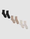 The Plush Modern Crew Sock 3-Pack by Cozy Earth is shown on a white background, featuring black, beige, and cream ribbed pairs, each with a small cuff tag.|Color:Black/Almond/Creme