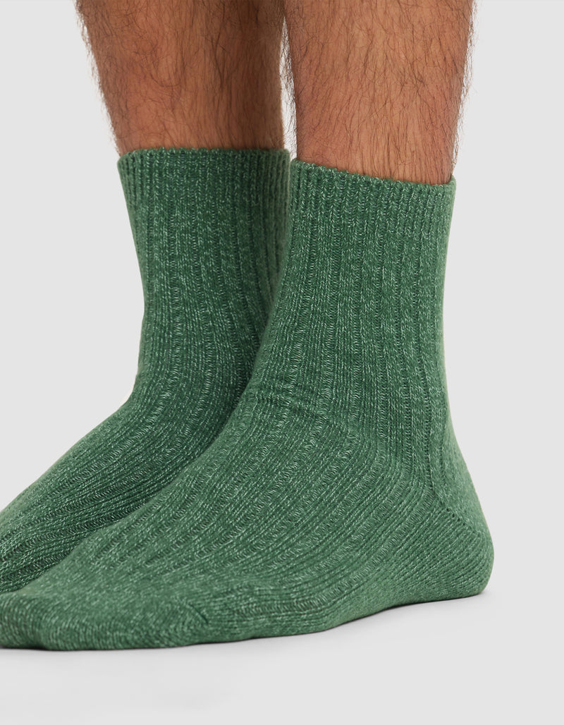 A close-up of lower legs and feet wearing Cozy Earth's Plush Lounge Quarter Sock 3-Pack in green, shown against a plain white background.
