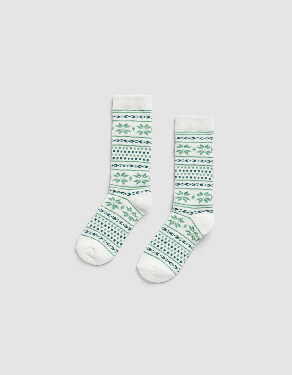 The Snowflake Plush Lounge Sock by Cozy Earth, a pair of white crew socks with green and blue geometric and floral patterns, displayed flat on a plain light gray background.