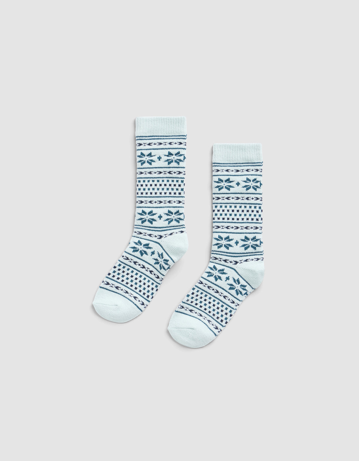 The Cozy Earth Snowflake Plush Lounge Sock features light blue fabric with dark blue geometric and snowflake stripes, shown on a plain light gray background.