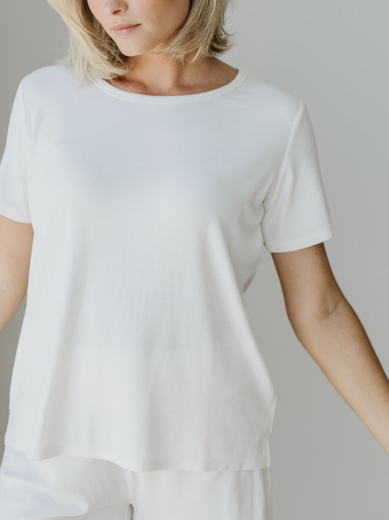 Woman wearing a white Cozy Earth Rib Knit Short Sleeve Lounge Top against a white background