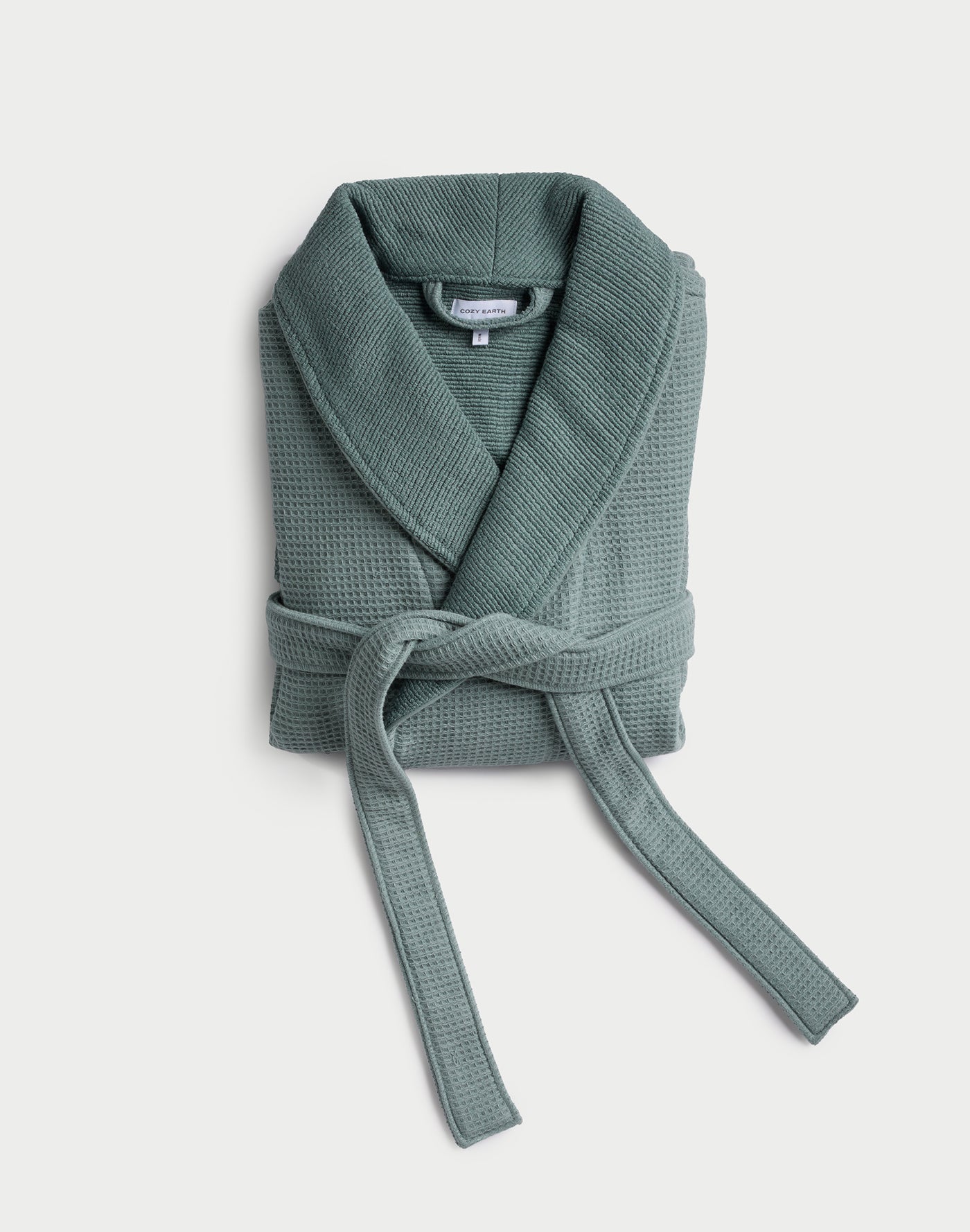 The Cozy Earth Waffle Bath Robe, shown folded with a shawl collar and tied belt in green waffle-knit fabric, is displayed against a plain white background. 