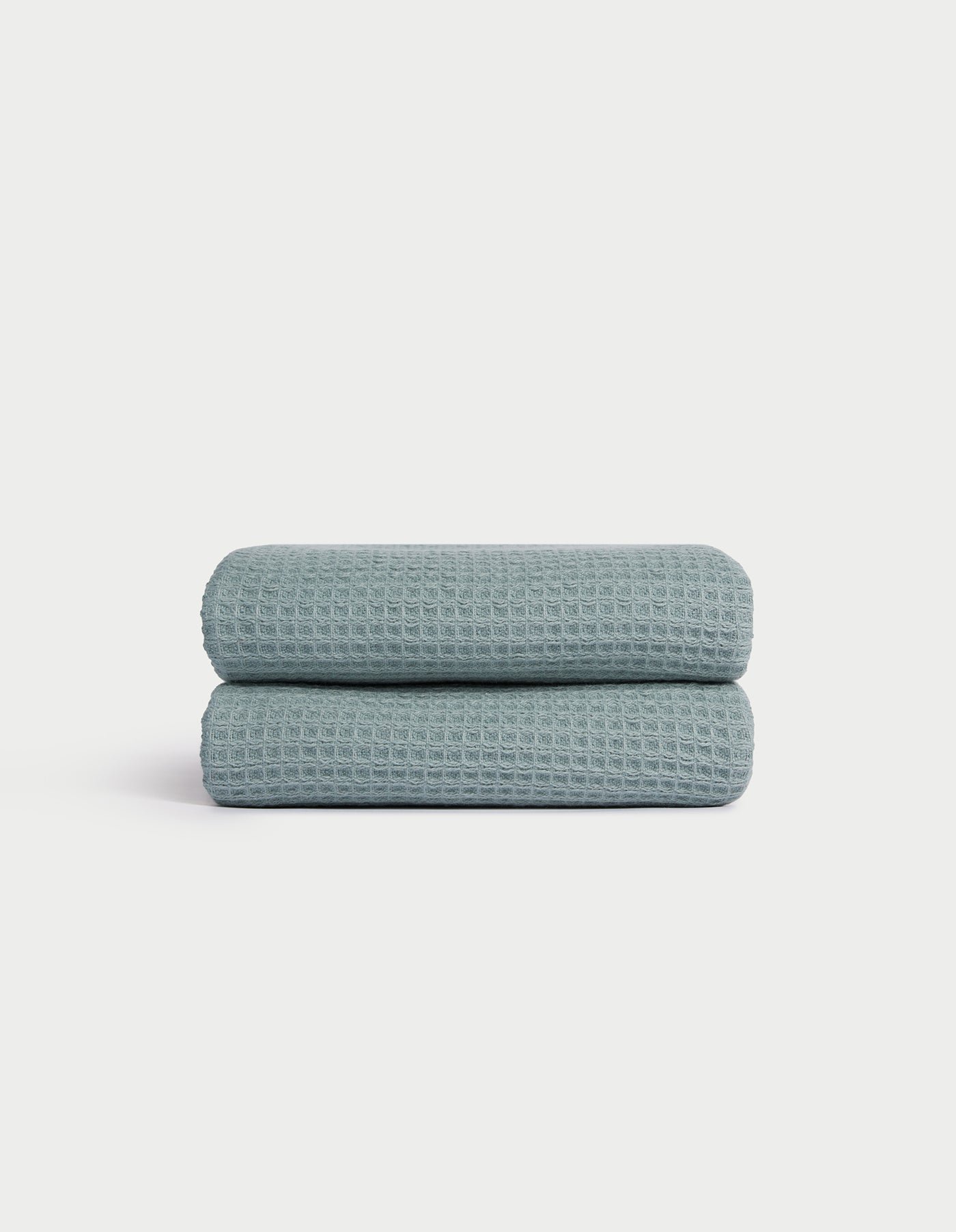 A folded Cozy Earth Waffle Hand Towel in light blue with a textured waffle pattern is displayed on a white background. |Color:Brook