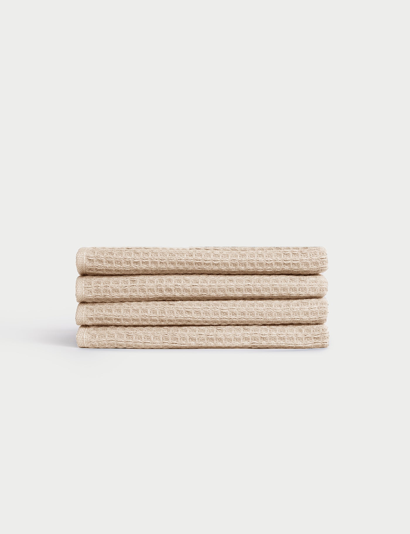Four neatly folded Cozy Earth Waffle Washcloths are stacked on top of each other against a white background. 