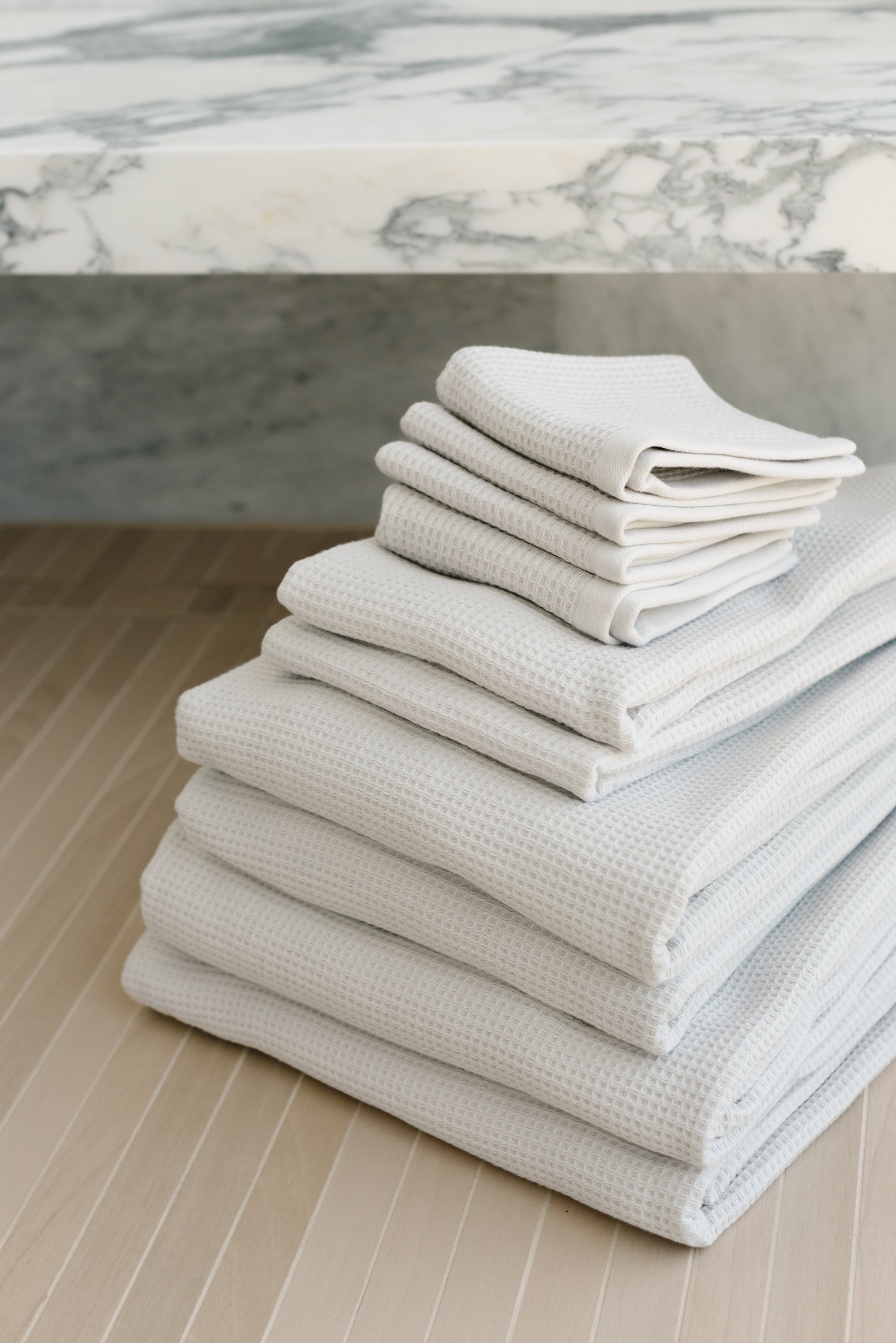 Complete Waffle Bath Bundle in the color Light Grey. Photo of Light Grey Complete Waffle Bath Bundle taken resting on floor of bathroom. 
