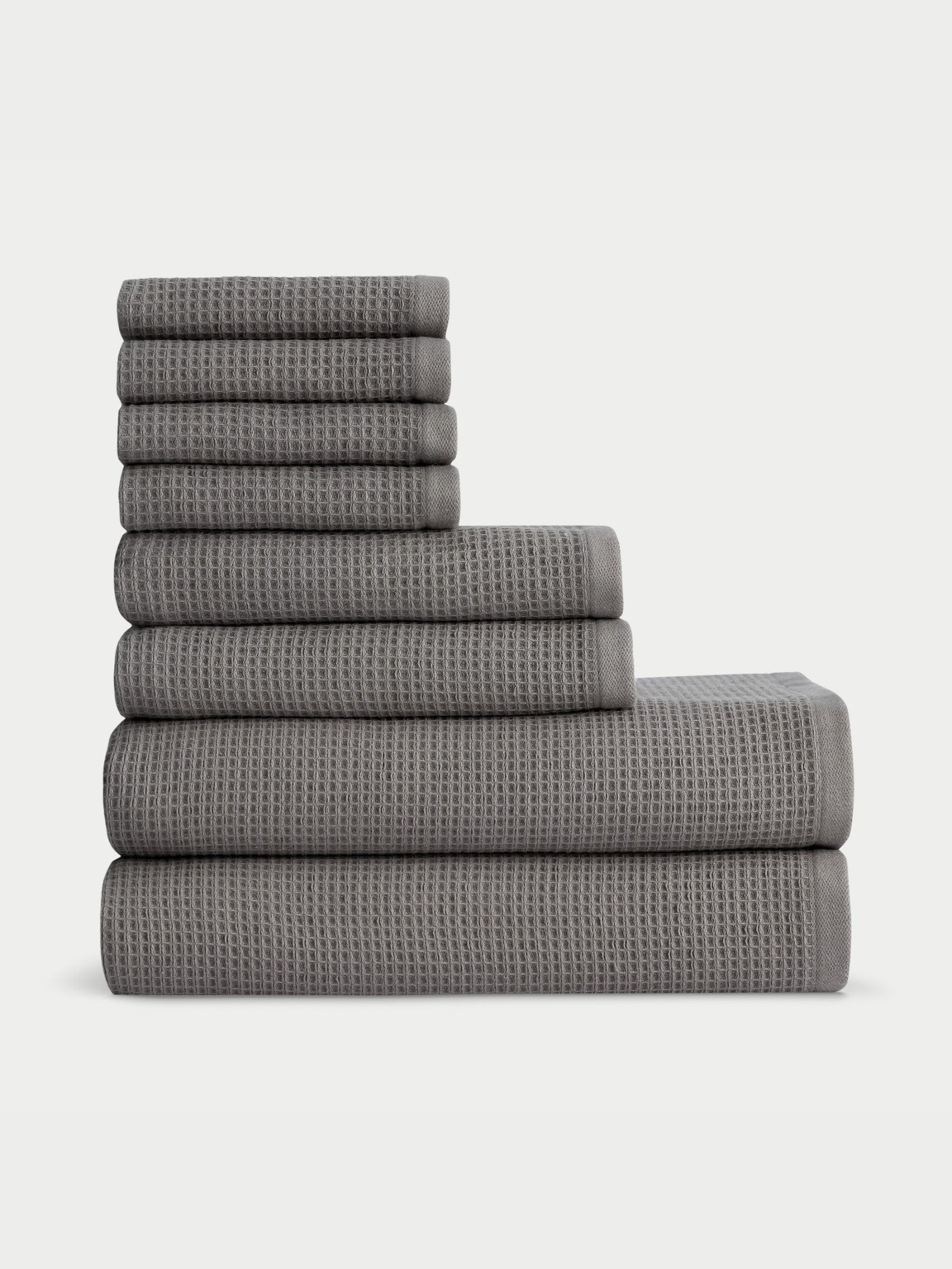 A stack of Cozy Earth's Waffle Bath Towel Set in various sizes, neatly folded against a light background. The set is organized in descending order with the thickest towel at the bottom and the thinnest on top.