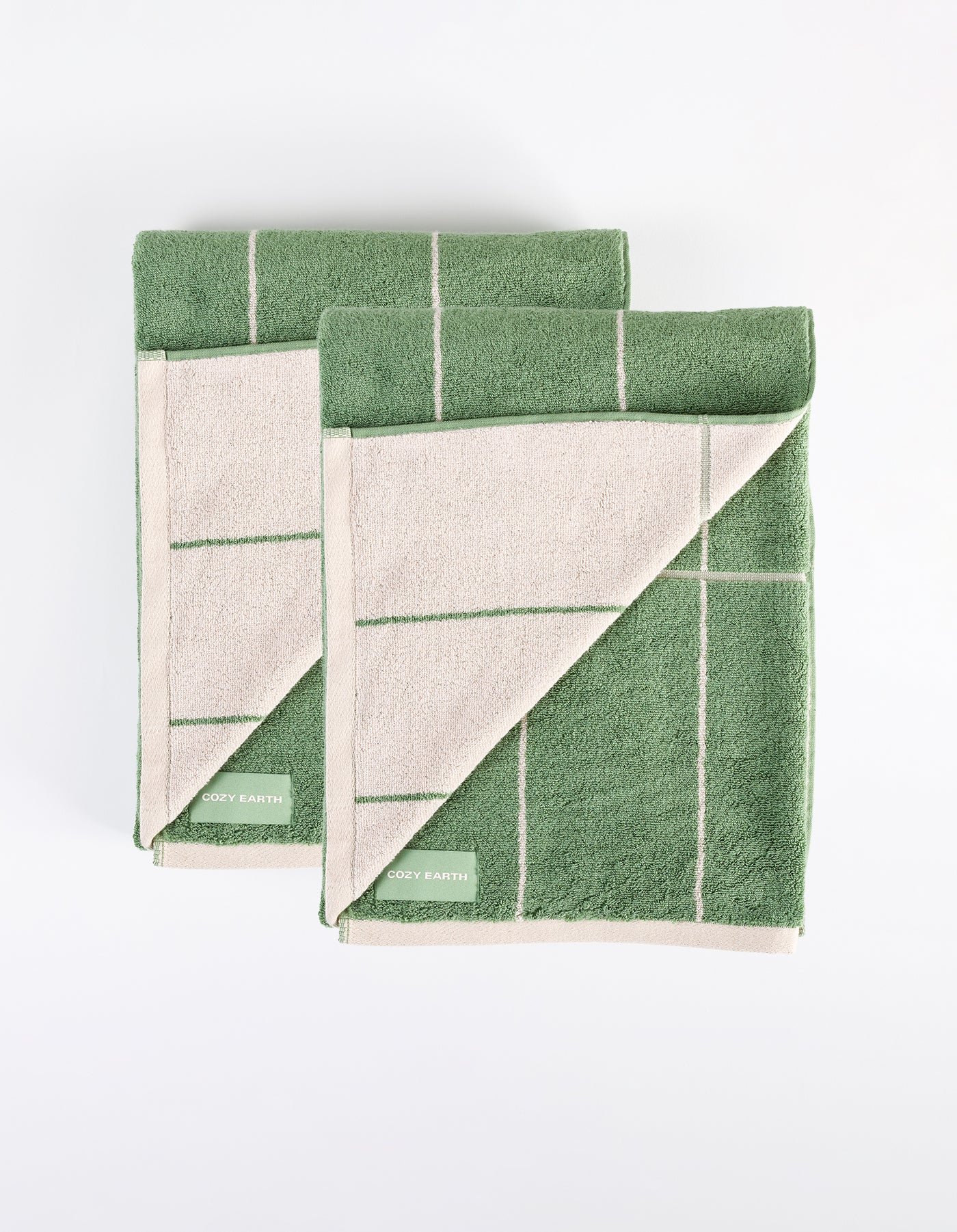 Two folded Windowpane Resort Towels from Cozy Earth, featuring a green and beige checkered pattern with visible "Cozy Earth" labels, are displayed on a white surface showing both sides. |Color:Prickly Pear