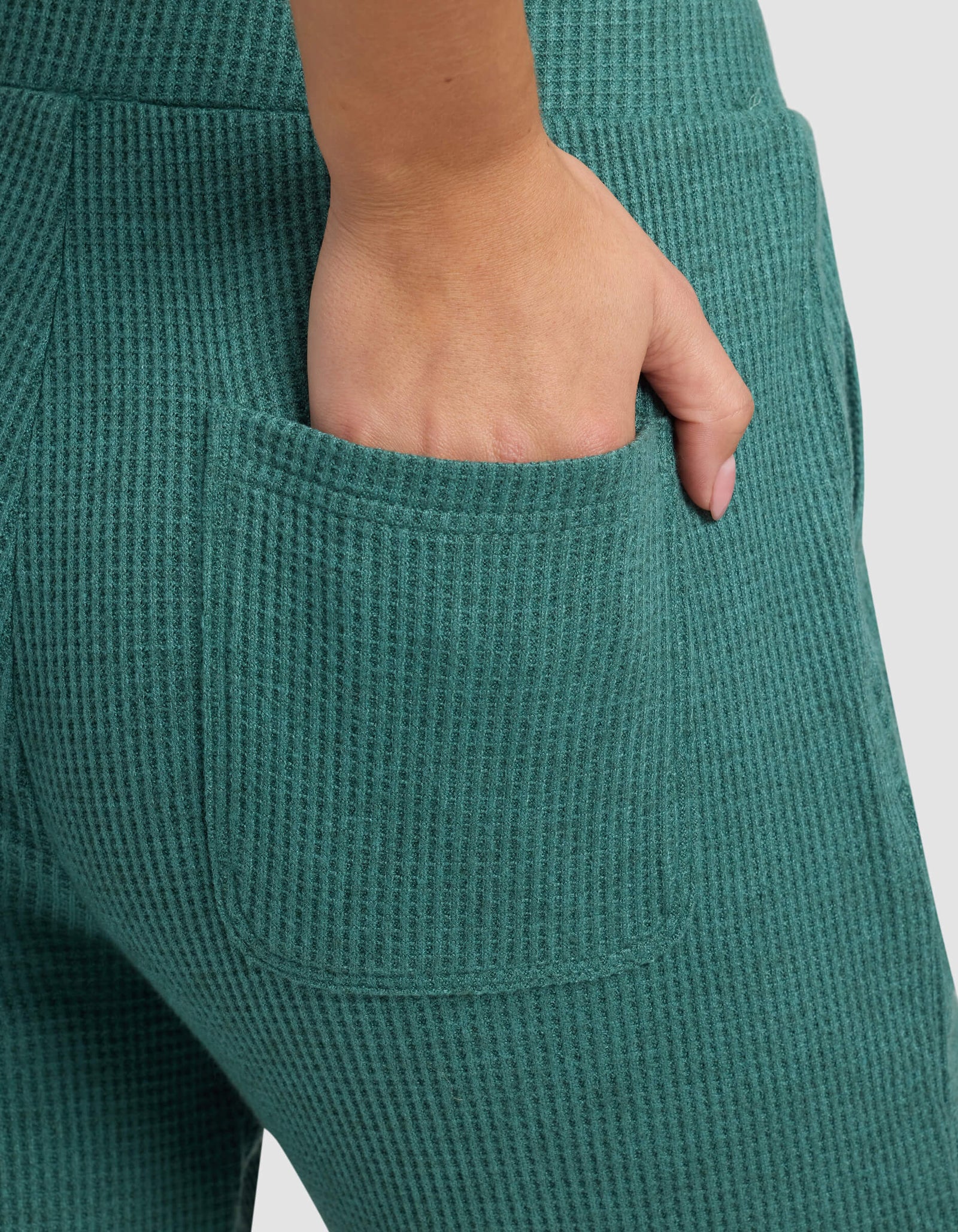 Close-up of a hand resting in the back pocket of Cozy Earth's Women's Blake Waffle Jogger in teal green, showcasing the ribbed knit texture and detailed stitching.