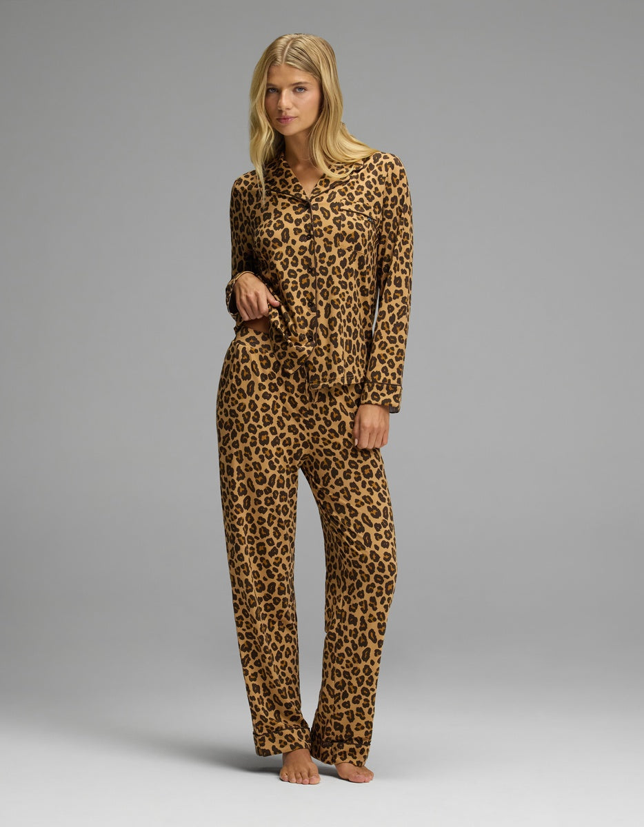 A woman wearing a button-down pajama top and matching Women’s Bamboo Stretch-Knit Pajama Pant in a brown leopard print pattern.