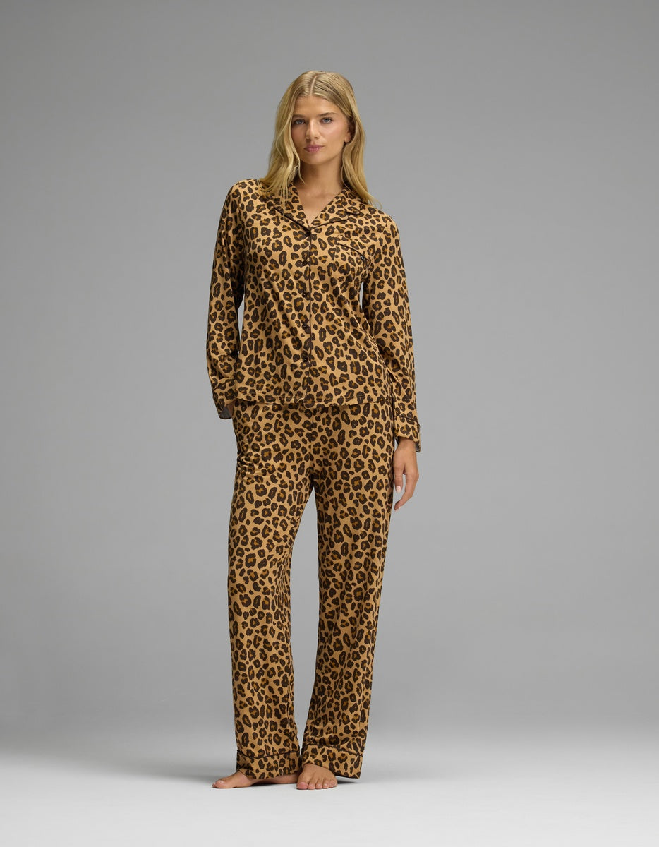 A woman wearing a brown and black leopard print Cozy Earth Women’s Bamboo Stretch-Knit Long Sleeve Pajama Top with matching trousers.