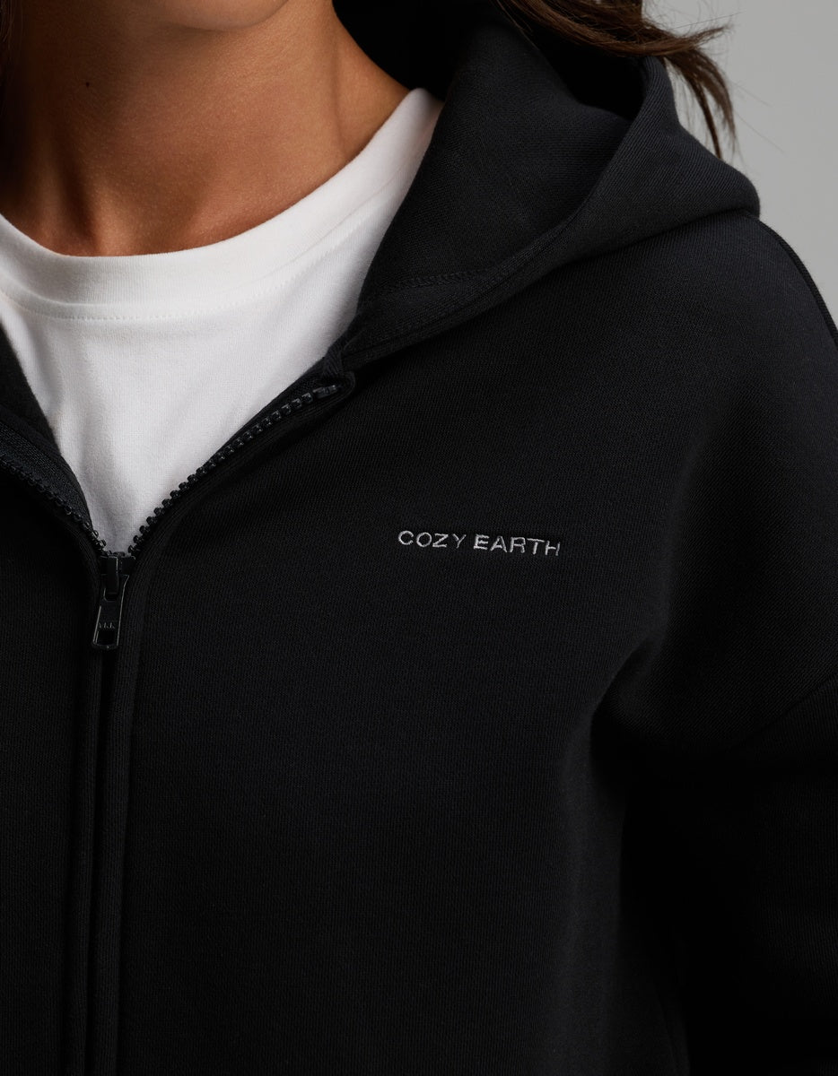 Black Cozy Earth Women’s CityScape Full-Zip Hoodie worn over a white t-shirt, featuring the brand name embroidered in small letters on the chest.