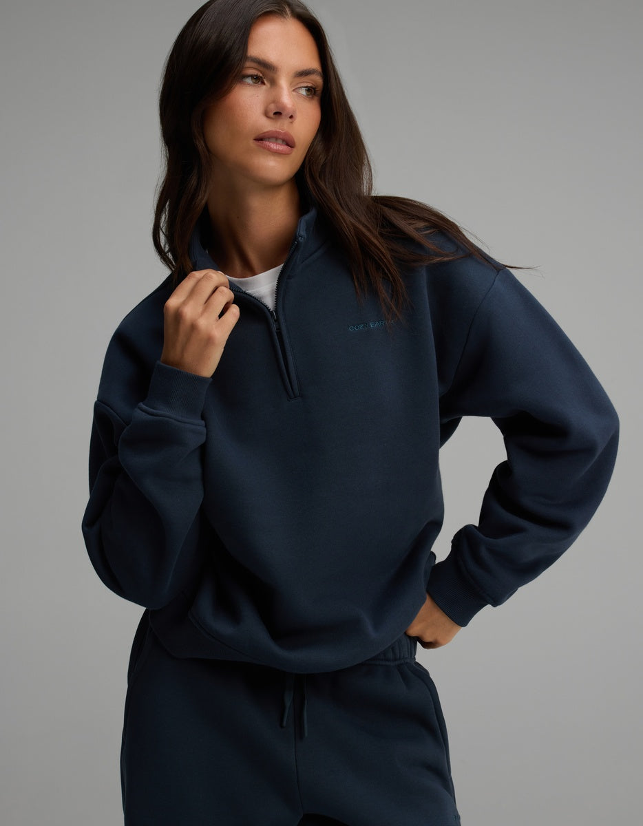 A woman wears a navy blue Women’s CityScape Quarter Zip, featuring a high collar.