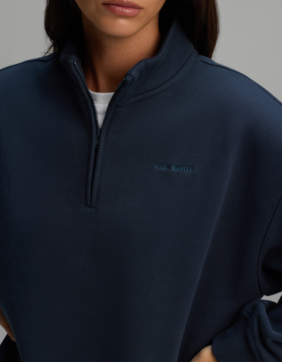 A navy blue Cozy Earth Women’s CityScape Quarter Zip featuring a high collar and a small embroidered brand name on the chest.
