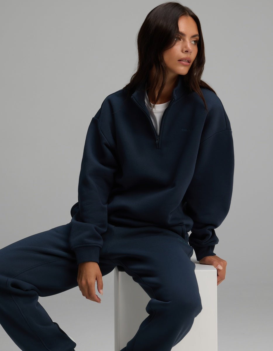 A person wearing a dark navy Women’s CityScape Quarter Zip and matching sweatpants.
