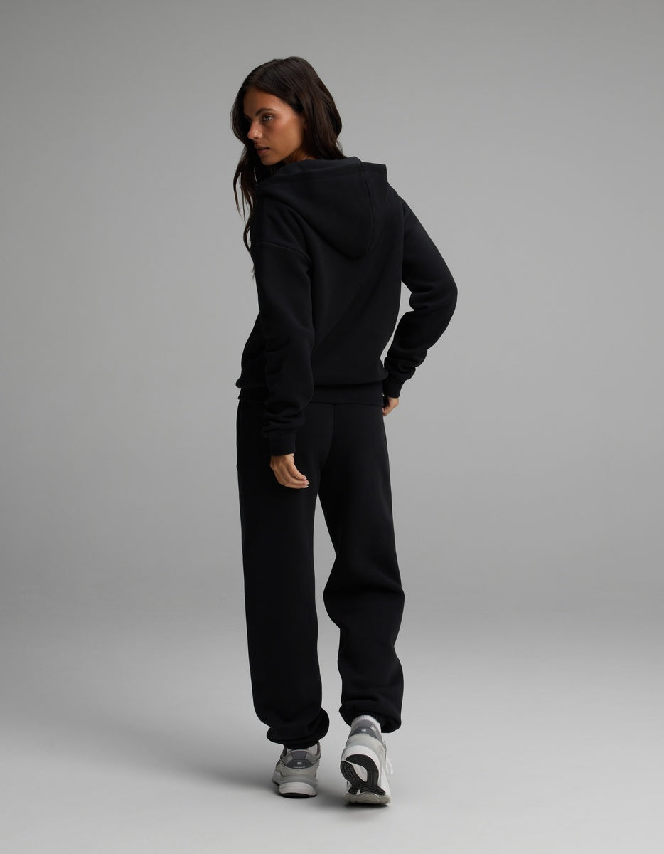 A person viewed from behind, wearing a black Women’s Cityscape Full-Zip Hoodie & Sweatpant Set.