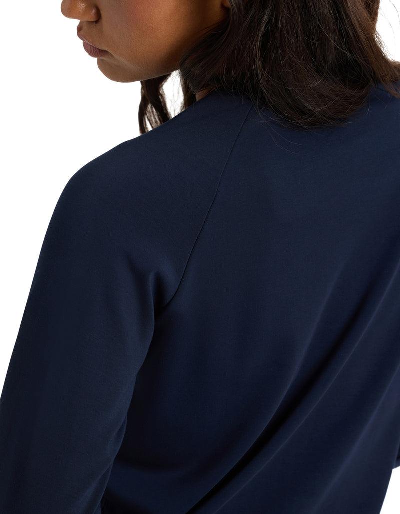A woman wears the Cozy Earth Women's Brushed Bamboo Pullover Crew, a long-sleeve dark blue top, shown from the side and back with her face partially visible.