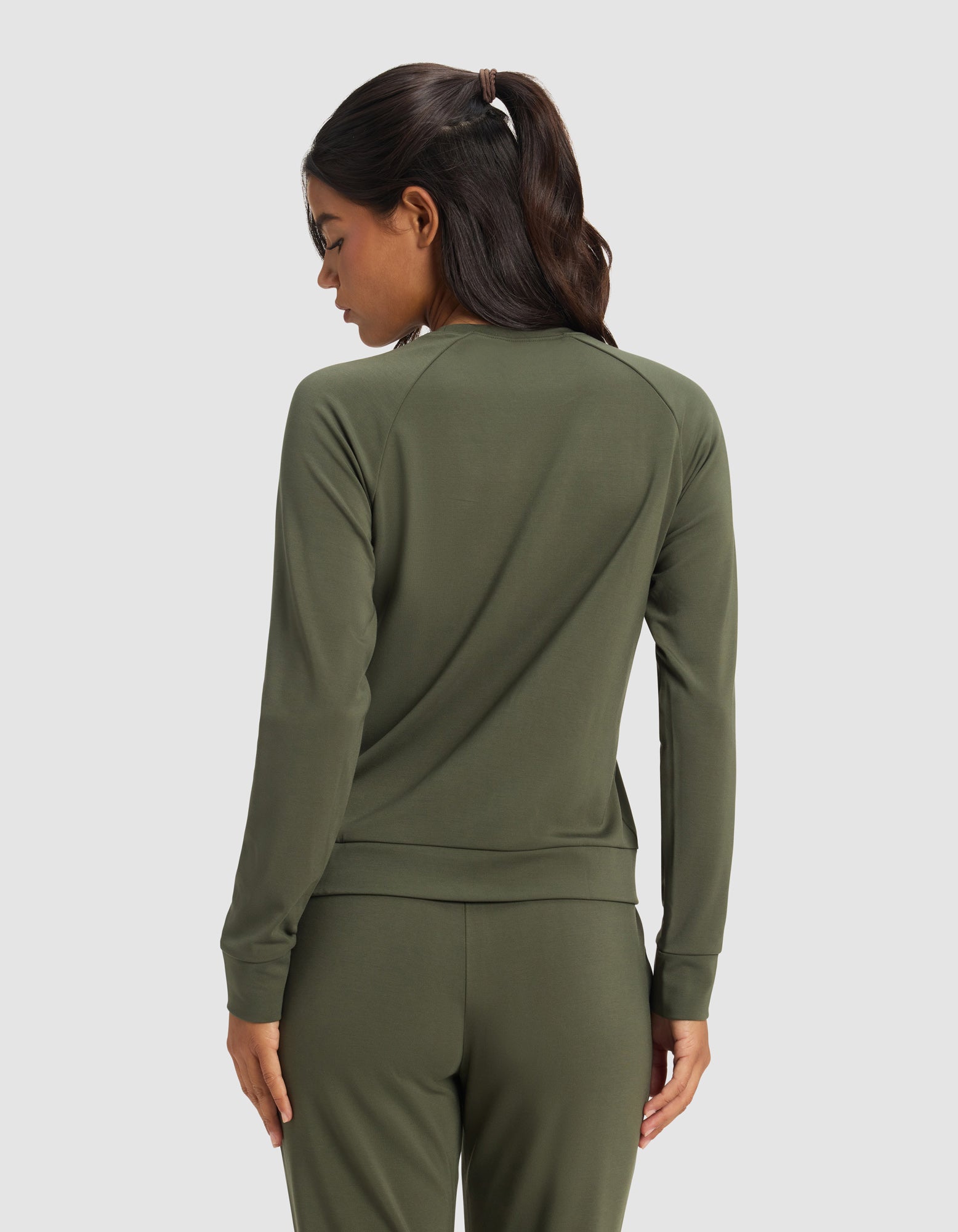A woman with dark hair in a ponytail models the Cozy Earth Women's Brushed Bamboo Pullover Crew in olive green, seen from the back against a plain light background.