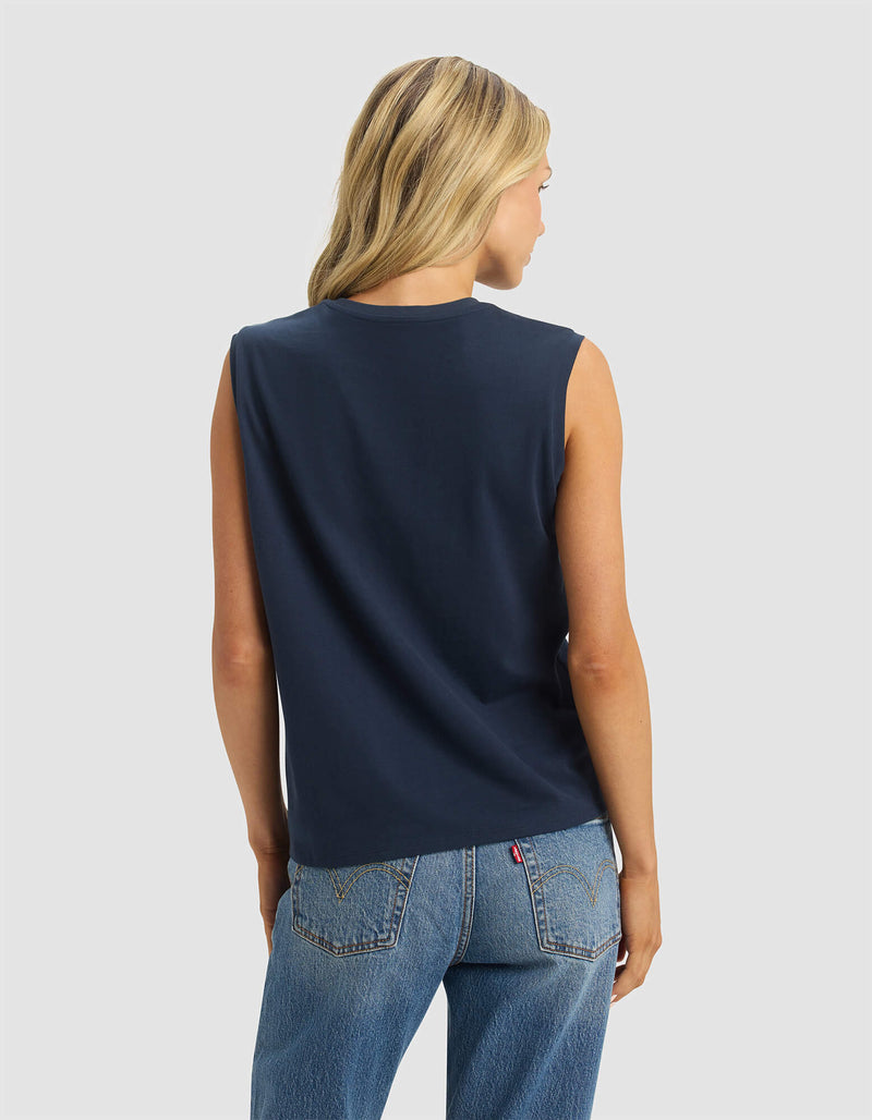 A woman with long blonde hair is shown from the back wearing the Cozy Earth Women's All Day Sleeveless Tee and blue jeans against a plain light background.