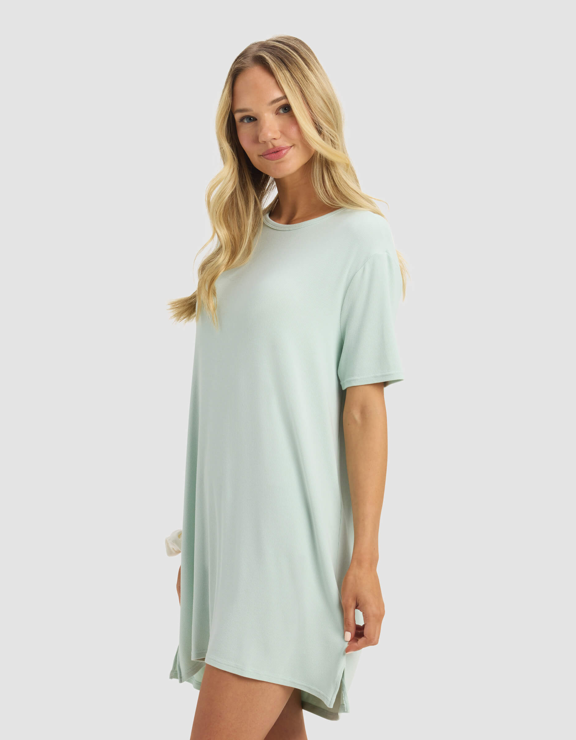 A woman with long blonde hair smiles against a light gray background, wearing the Cozy Earth Women's Bamboo Rib-Knit Boyfriend Dress in loose, light mint green short sleeves.|Color:Seafoam
