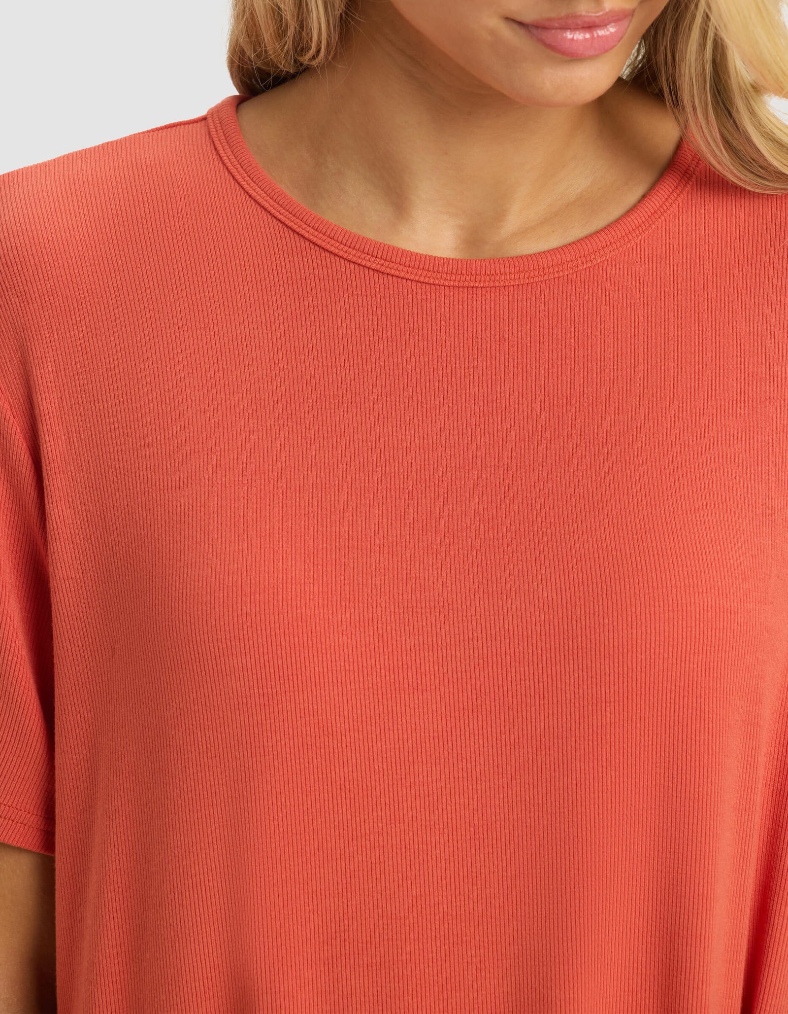 A woman wears the Cozy Earth Women's Bamboo Rib-Knit Boyfriend Dress in coral. The image is cropped from shoulders to upper chest, showing part of her face.