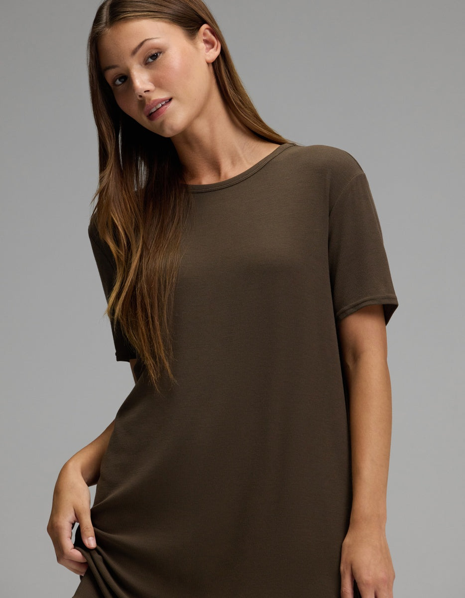 A woman with long brown hair stands against a plain gray background, wearing the Cozy Earth Women’s Bamboo Rib-Knit Boyfriend Sleep Dress.