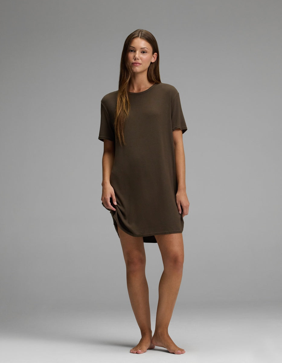 A woman stands barefoot on a plain backdrop, wearing the Cozy Earth Women’s Bamboo Rib-Knit Boyfriend Sleep Dress in brown. She faces forward with a relaxed posture and a neutral expression.|Color:Espresso